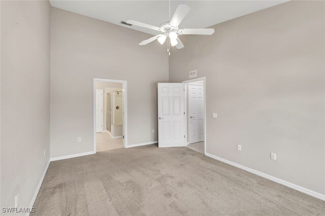 unfurnished bedroom featuring a high ceiling, light colored carpet, and ceiling fan