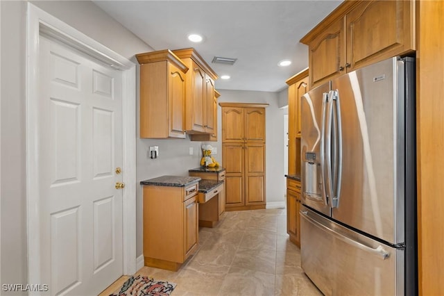 kitchen featuring stainless steel fridge with ice dispenser and dark stone countertops