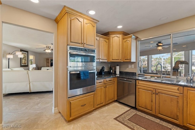 kitchen with ceiling fan, stainless steel appliances, dark stone countertops, and sink