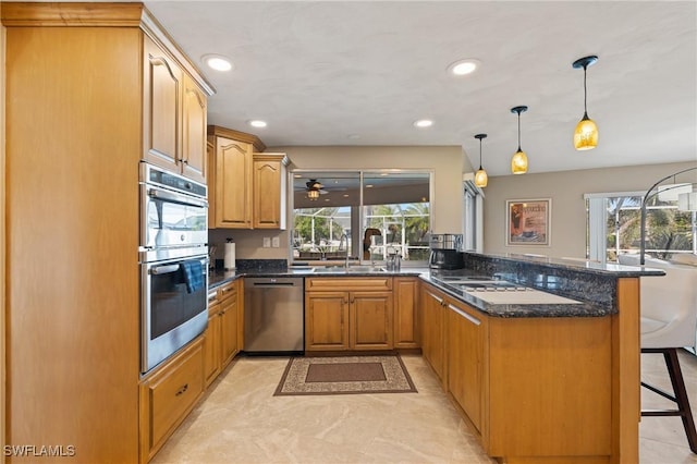 kitchen featuring kitchen peninsula, stainless steel appliances, a kitchen breakfast bar, hanging light fixtures, and sink