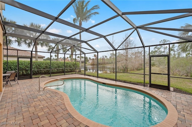 view of pool featuring glass enclosure, a water view, and a patio