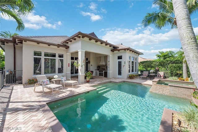 rear view of house featuring exterior kitchen, a patio, and a swimming pool with hot tub