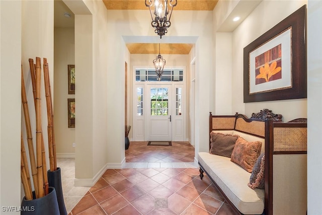 tiled entrance foyer featuring a chandelier and baseboards