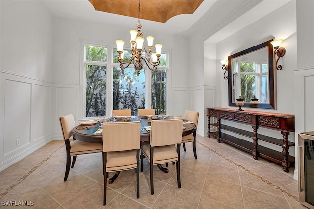 dining room featuring a raised ceiling, a decorative wall, plenty of natural light, and light tile patterned floors