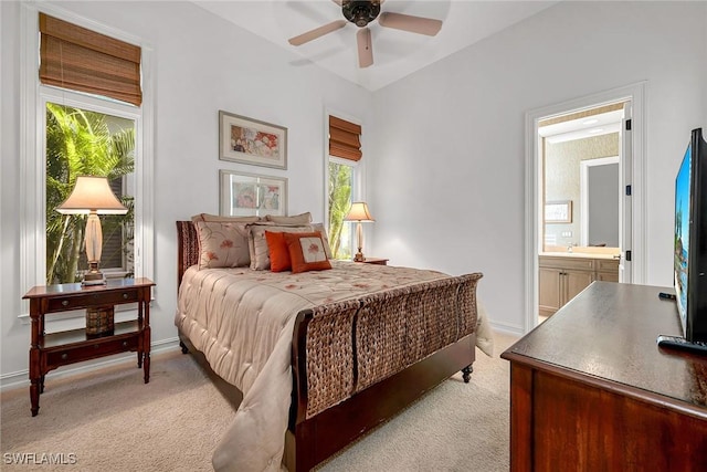 bedroom with ceiling fan, light colored carpet, baseboards, and connected bathroom