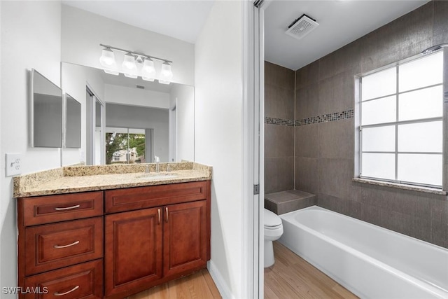 bathroom featuring a healthy amount of sunlight, hardwood / wood-style floors, a washtub, and toilet