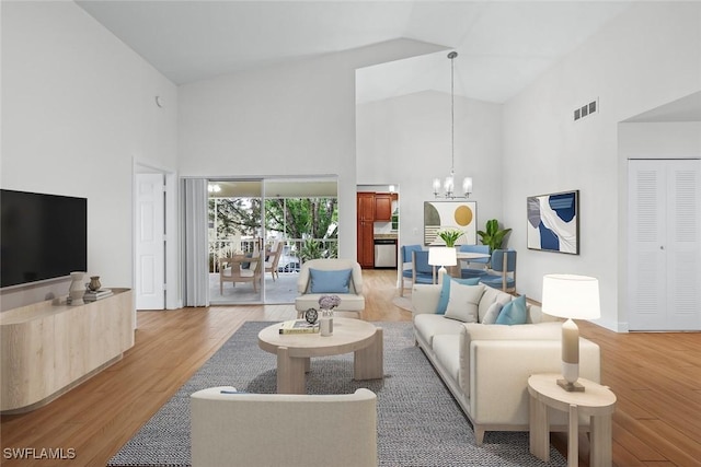 living room with hardwood / wood-style flooring, a chandelier, and high vaulted ceiling