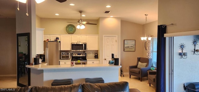 kitchen featuring stainless steel appliances, kitchen peninsula, white cabinetry, decorative light fixtures, and tasteful backsplash