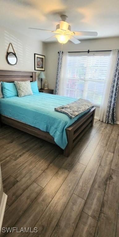 bedroom with dark hardwood / wood-style flooring, ceiling fan, and multiple windows