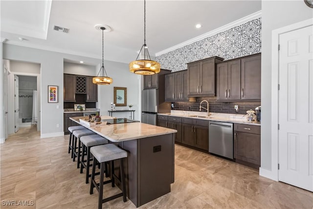 kitchen with appliances with stainless steel finishes, a center island, hanging light fixtures, dark brown cabinetry, and sink