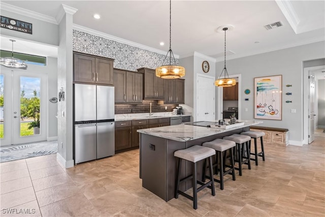 kitchen with dark brown cabinetry, appliances with stainless steel finishes, ornamental molding, a breakfast bar, and a center island with sink