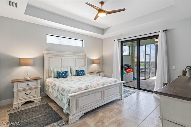 bedroom featuring ceiling fan, access to exterior, and a tray ceiling