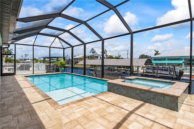 view of pool featuring glass enclosure, an in ground hot tub, and a patio