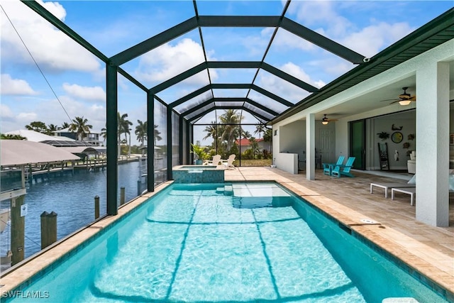 view of swimming pool featuring ceiling fan, a patio area, an in ground hot tub, glass enclosure, and a water view