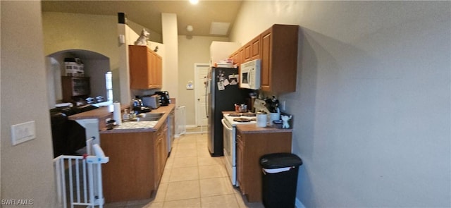 kitchen with light tile patterned floors, vaulted ceiling, and white appliances