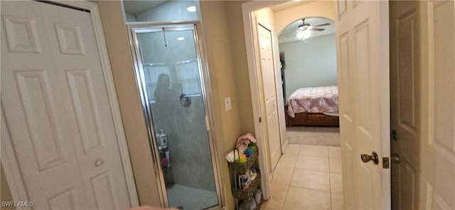 bathroom with ceiling fan, a shower with door, and tile patterned flooring