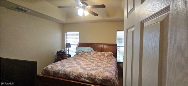 bedroom with ceiling fan and a tray ceiling