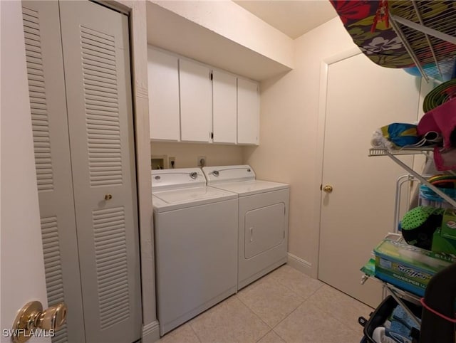 laundry area featuring cabinets, light tile patterned floors, and washing machine and clothes dryer