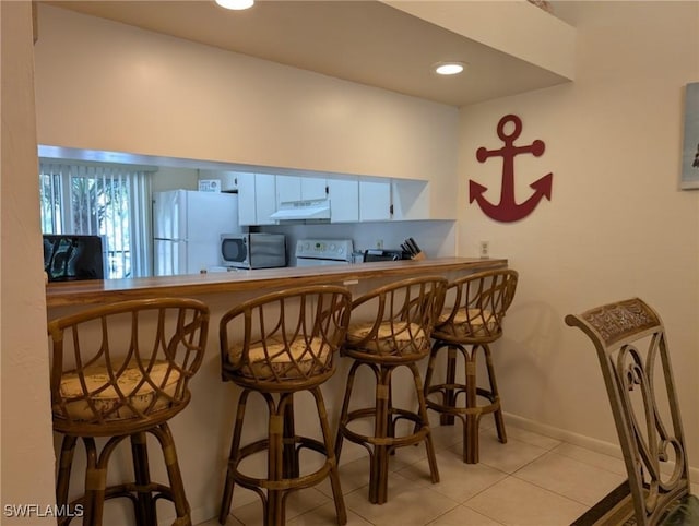 bar featuring electric range oven, light tile patterned floors, white refrigerator, and white cabinetry