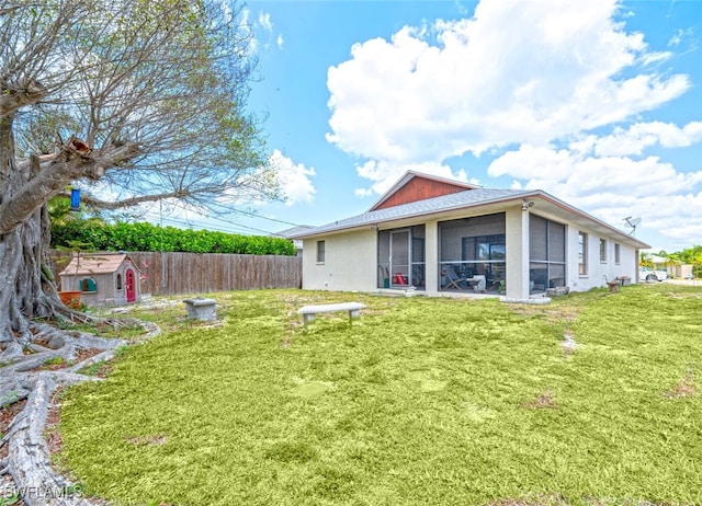 back of property with a shed, a sunroom, and a lawn