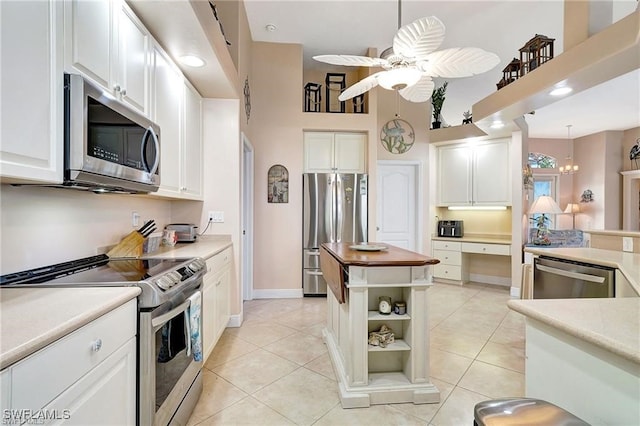 kitchen featuring light tile patterned floors, ceiling fan, a kitchen island, and appliances with stainless steel finishes