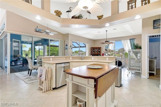 kitchen featuring a ceiling fan, a center island, a wealth of natural light, and stainless steel dishwasher