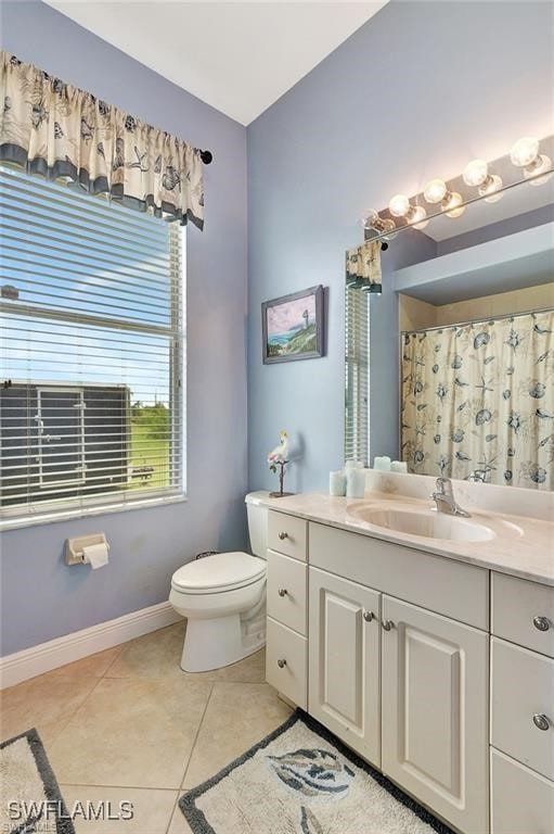 bathroom with curtained shower, tile patterned flooring, toilet, vanity, and baseboards