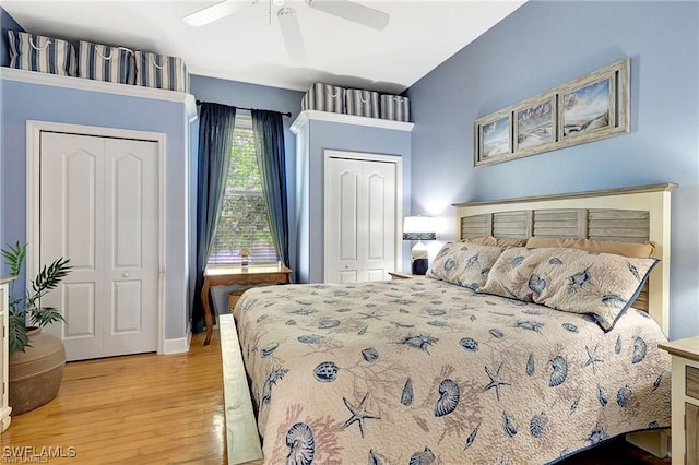 bedroom with light wood-style floors, ceiling fan, and two closets