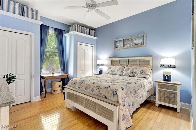 bedroom with baseboards, wood-type flooring, and multiple closets