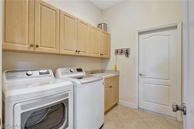 washroom with light tile patterned floors, a sink, baseboards, cabinet space, and washer and clothes dryer