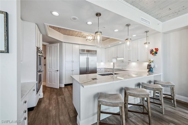 kitchen featuring white cabinets, stainless steel appliances, kitchen peninsula, and pendant lighting