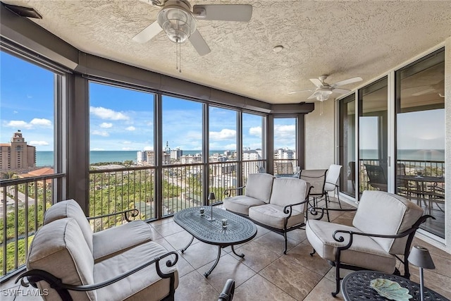 sunroom featuring ceiling fan and a water view