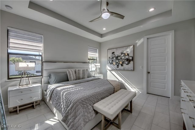 bedroom with ceiling fan and a raised ceiling