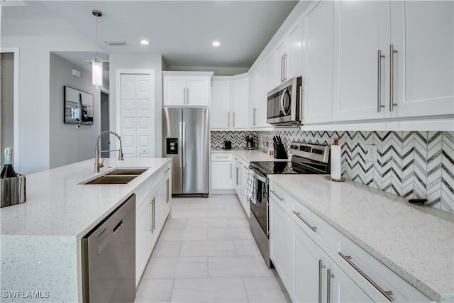 kitchen with sink, white cabinetry, hanging light fixtures, stainless steel appliances, and light stone counters