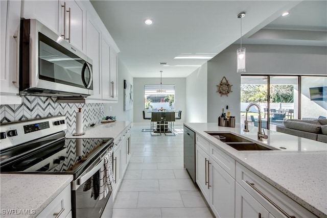 kitchen with decorative backsplash, sink, hanging light fixtures, appliances with stainless steel finishes, and light stone counters