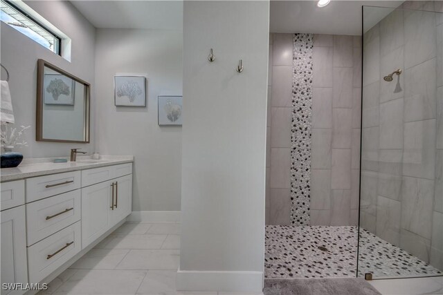 bathroom with tile patterned floors, tiled shower, and vanity