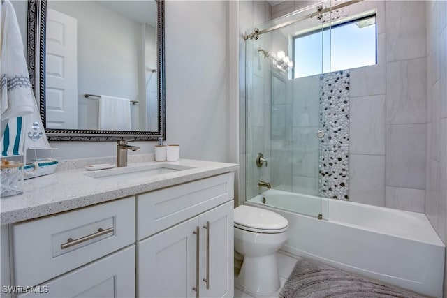 full bathroom with combined bath / shower with glass door, vanity, and toilet