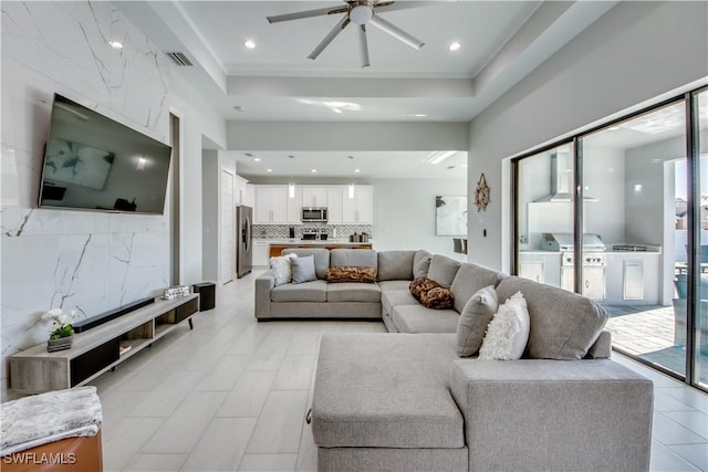 living room featuring ceiling fan, washing machine and clothes dryer, and a raised ceiling