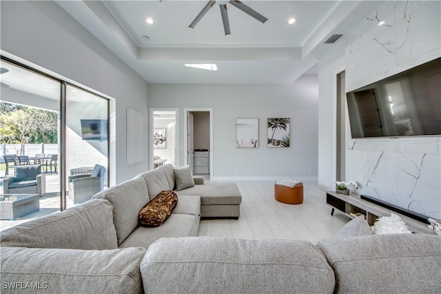 living room featuring ceiling fan and a tray ceiling