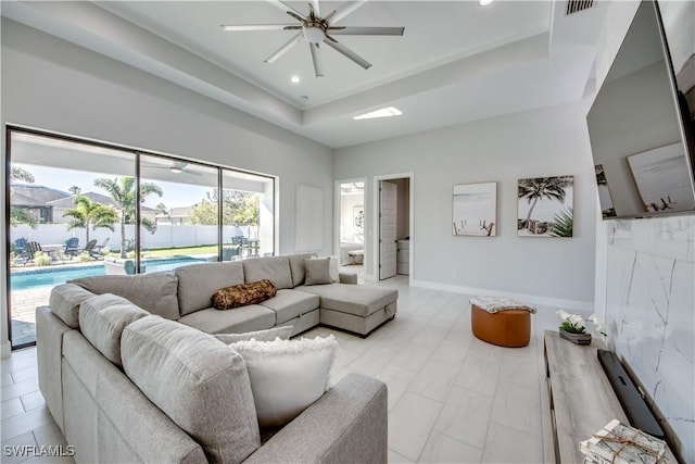 living room featuring ceiling fan and a raised ceiling