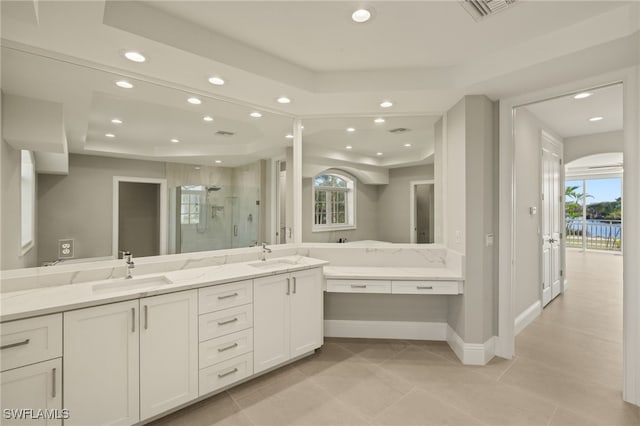 bathroom with a healthy amount of sunlight, a shower with door, a raised ceiling, and vanity