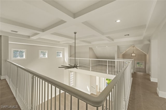 hallway featuring coffered ceiling, dark tile patterned flooring, and beam ceiling