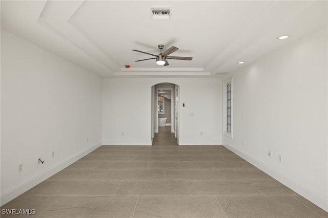 unfurnished room featuring ceiling fan and a raised ceiling