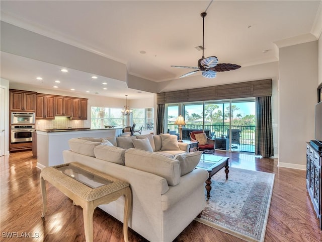 living room featuring ceiling fan with notable chandelier, crown molding, and light hardwood / wood-style flooring