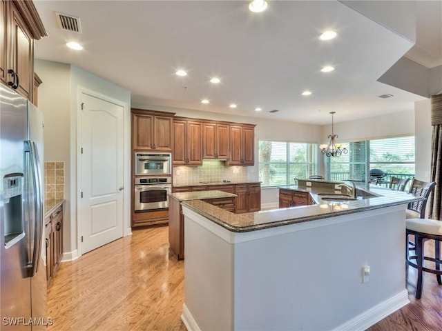 kitchen featuring a large island, a chandelier, appliances with stainless steel finishes, hanging light fixtures, and sink