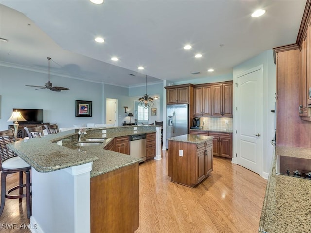 kitchen featuring a large island with sink, stainless steel appliances, light stone counters, and sink