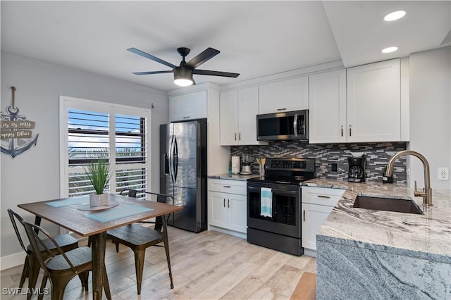 kitchen featuring light stone countertops, electric stove, refrigerator with ice dispenser, white cabinets, and sink