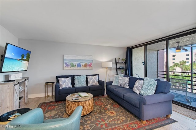 living room featuring ceiling fan, a wall of windows, and hardwood / wood-style floors