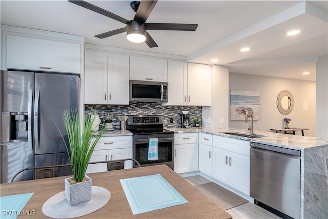 kitchen with light stone countertops, decorative backsplash, white cabinets, appliances with stainless steel finishes, and sink