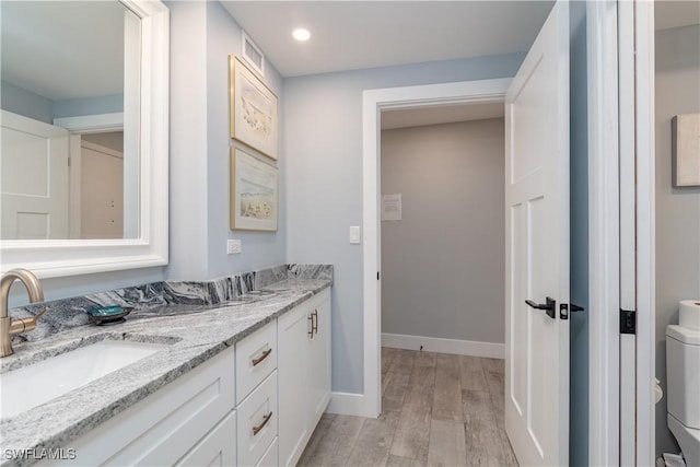 bathroom featuring toilet, vanity, and hardwood / wood-style flooring